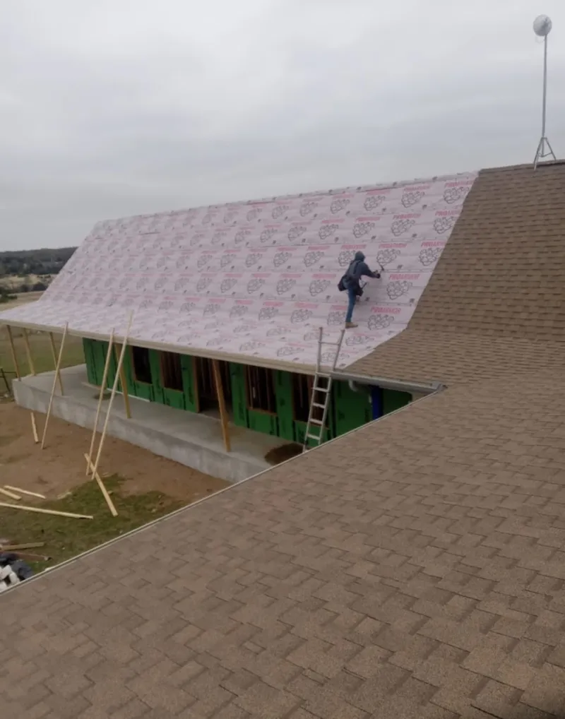 Worker preparing underlayment for a metal roof installation in Hartland
